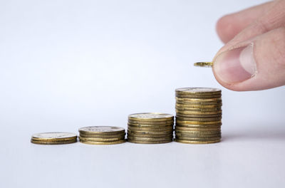 Close-up of hand holding stack of objects on table against white background