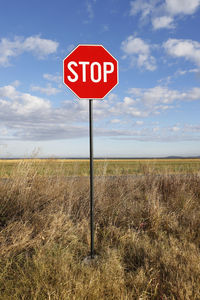 Information sign on field against sky