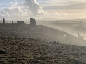 People walking on mountain against sky during sunset