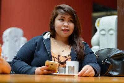 Portrait of young woman using mobile phone in restaurant