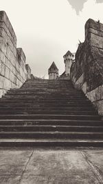 Low angle view of staircase amidst buildings against sky