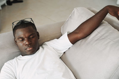 High angle view of man lying down on sofa at home