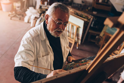 High angle view of mature man painting on canvas
