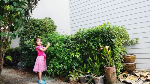 Portrait of cute girl standing by flowering plant