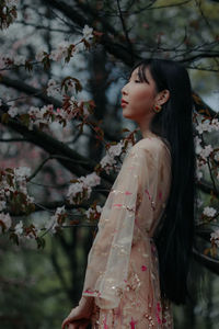 Young woman standing against trees