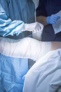 Midsection of doctor applying bandage on patient leg at hospital