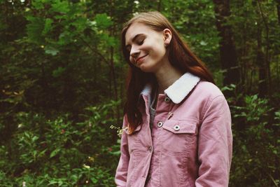 Portrait of a smiling young woman standing against trees