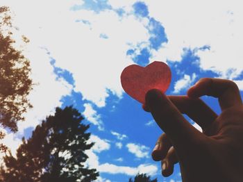 Low angle view of cropped hand against sky