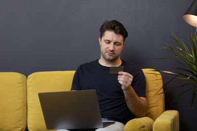 Young man using mobile phone while sitting on sofa