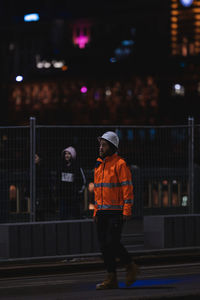 Rear view of man walking on illuminated street at night