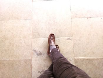 Low section of man standing on tiled floor