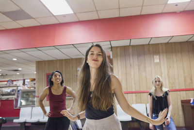 A young woman bowling with friends.