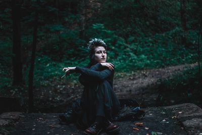 Portrait of young woman sitting in forest