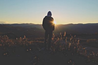 Rear view of silhouette man standing on mountain against sky