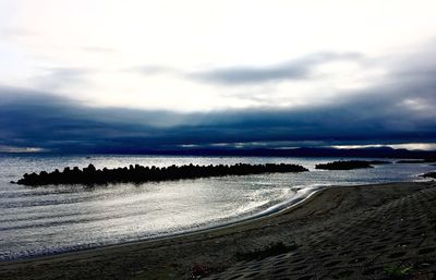 Scenic view of beach against cloudy sky