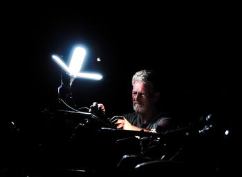 Senior man repairing motorcycle in darkroom