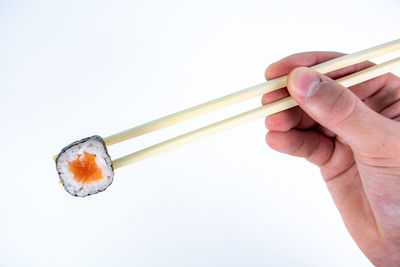 Close-up of hand holding fork over white background