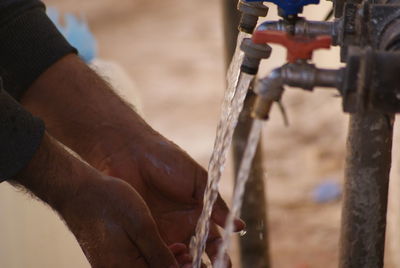 Cropped image of man washing hands outdoors