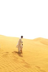 Full length of man walking on sand against clear sky