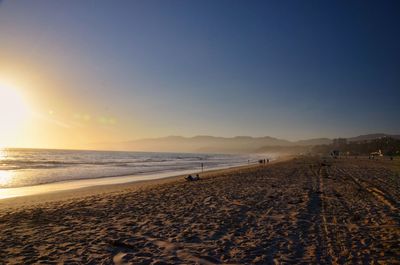Scenic view of beach against clear sky during sunset