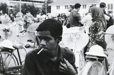 Young man smoking cigarette while looking away in city