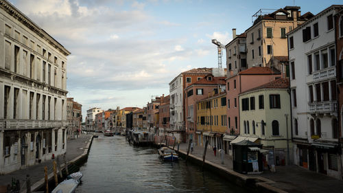 Canal amidst buildings in city against sky