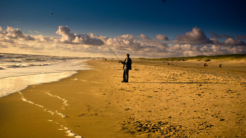 Full length of man fishing while standing at beach