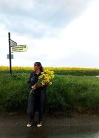 Woman with arms raised on field against sky