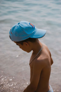 Side view of shirtless boy standing in sea during summer