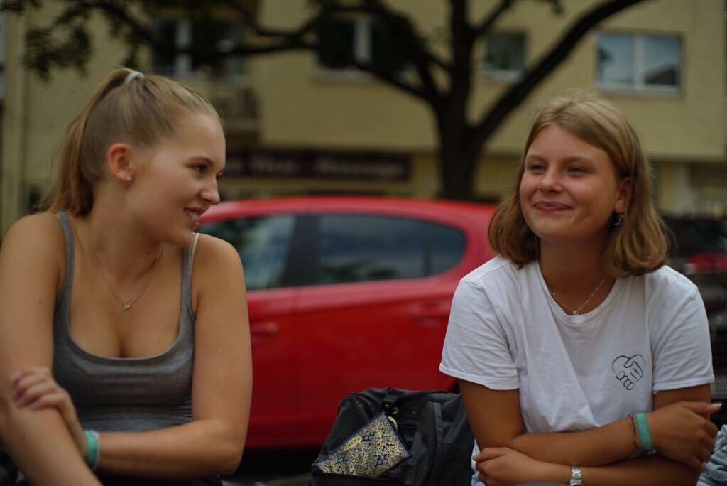 sitting, smiling, two people, building exterior, car, outdoors, happiness, cheerful, day, girls, blond hair, togetherness, architecture, friendship, people, young adult, adult