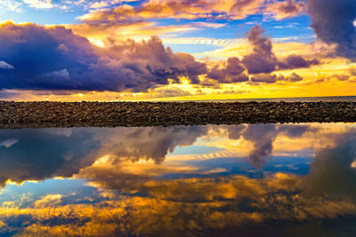 Scenic view of sea against dramatic sky during sunset