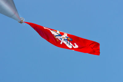 Low angle view of flag against clear blue sky