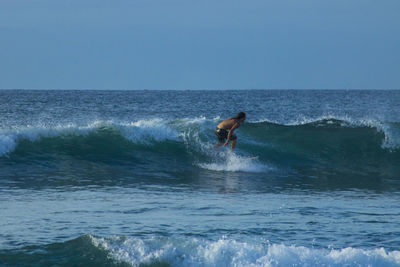 Man surfing in sea against clear sky
