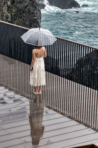 Rear view of woman with umbrella walking on street