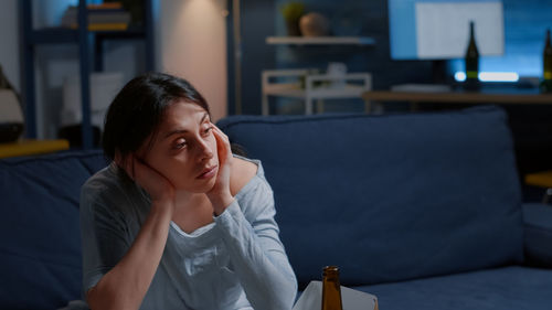 Young woman looking away while sitting at home