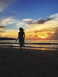 Silhouette man on beach against sky during sunset