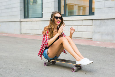Young woman sitting on skateboard