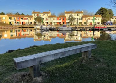 Buildings by lake against sky