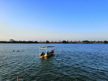 Boat sailing in sea against clear blue sky