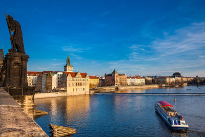 Buildings at waterfront against cloudy sky