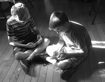 High angle view of two boys sitting on floor in sunlight