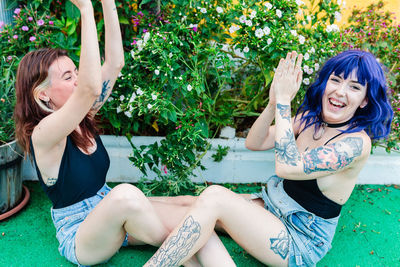 Happy young women playing patty cake in backyard