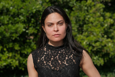 Portrait of young woman standing against plants