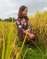 Young woman looking away on field against sky