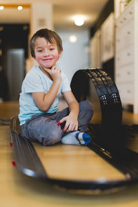 Portrait of boy sitting amidst toy racetrack
