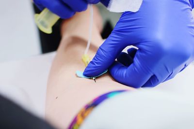 Cropped image of doctor giving iv drip to patient in hospital