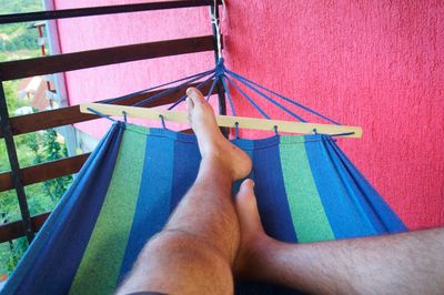 Low section of man relaxing on hammock at home