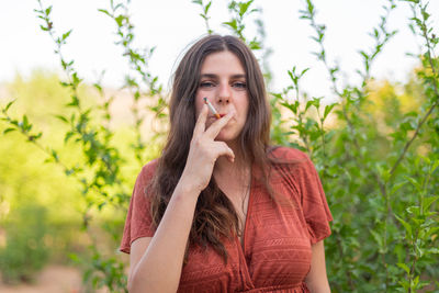 Happy young woman smoking in the countryside