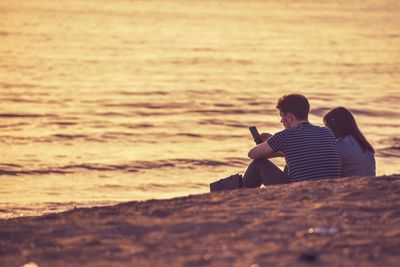 Rear view of couple sitting on beach