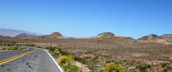 Road by mountains against clear blue sky